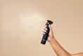 Load image into Gallery viewer, Tricoci Blowout Spray being applied to hair, demonstrating proper pre-styling application technique